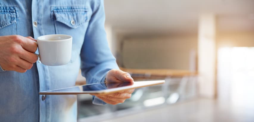 Close up of a male hands holding digital tablet and cup of coffee