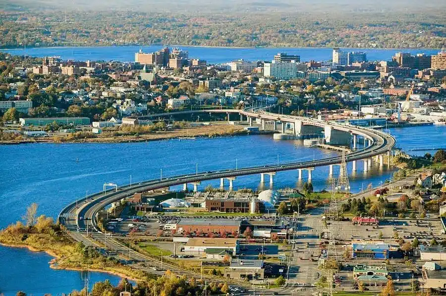 ME - Aerial view of a city in Maine with a winding bridge crossing a river, connecting urban and suburban areas.