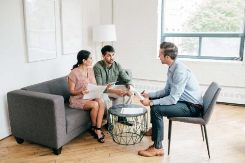 Patient real estate agent discusses pros and cons of each house with a couple.